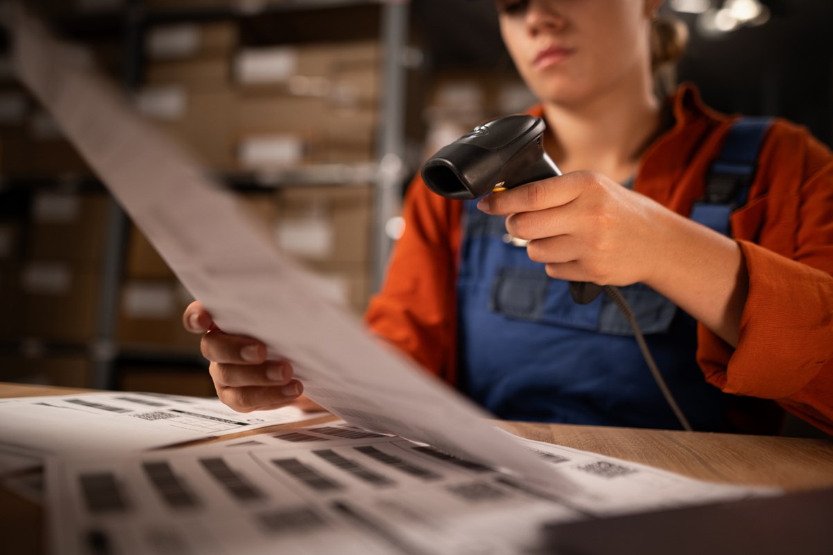 A warehouse employee scanning barcodes into an inventory management ERP system to keep track of shipping.